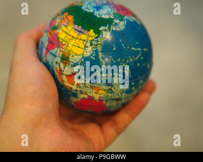 Close Up Hand holding a Mini Globe with Wooden Table Background Stock Photo
