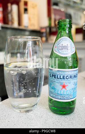 S.Pelligrino Sparkling mineral water bottle and glass with ice and lemon in an Italian Cafe Stock Photo