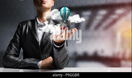 Woman presenting flying balloon in hand. Stock Photo