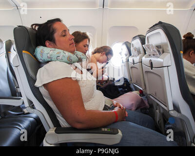 A lady sleeping on a passenger aircraft using a neck pillow Stock Photo