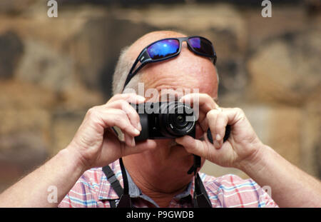 Man wearing sunglasses on his head taking a photograph Stock Photo