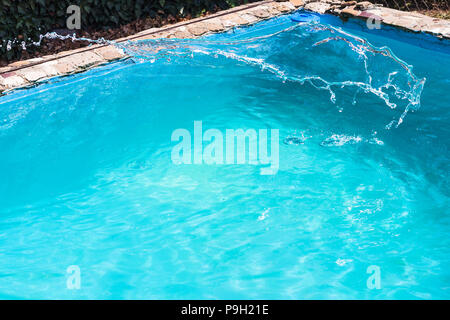 splashing of disinfectant in outdoor swimming pool on backyard of country house Stock Photo