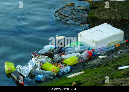 Discarded plastic waste floating on the edge of a harbour slipway contaminating the oceans Stock Photo