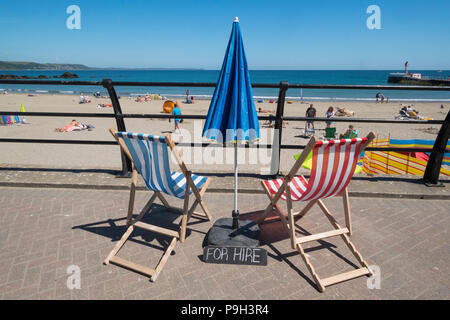 Deckchairs and parasol  for hire at the fishing port of Looe, Cornwall, England, UK. Stock Photo