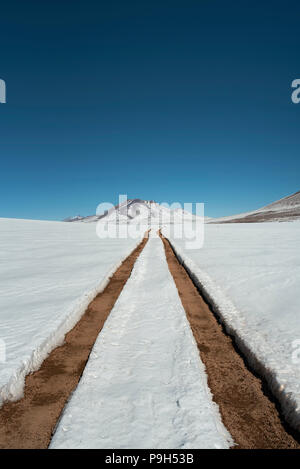 Wintery landscape and snow covered road with car tracks in Eduardo Avaroa Andean Fauna National Reserve, Bolivia, South America. Jun 2018 Stock Photo