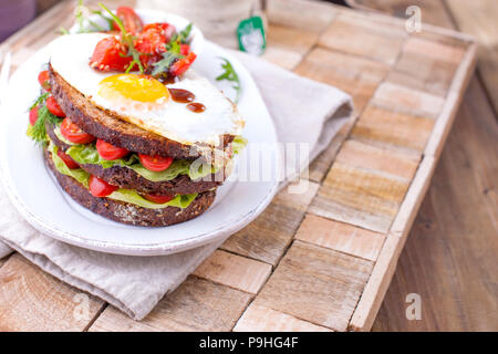 Toast from a grain bread with cheese and tomatoes and egg. Vegetarian food. on a white plate and a wooden background. Useful breakfast. Free space for writing text Stock Photo