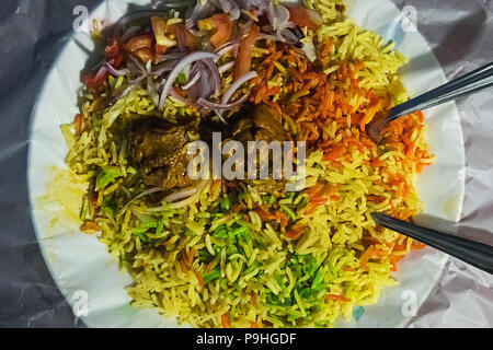Fried rice nasi goreng with chicken and vegetables on a pan. Traditional Indian fried rice briyani. green yellow and red rice. Multicolored rice in a  Stock Photo