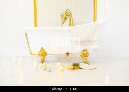 Bathroom with candles, book, glass of champagne by the bath on the marble tiled floor Stock Photo