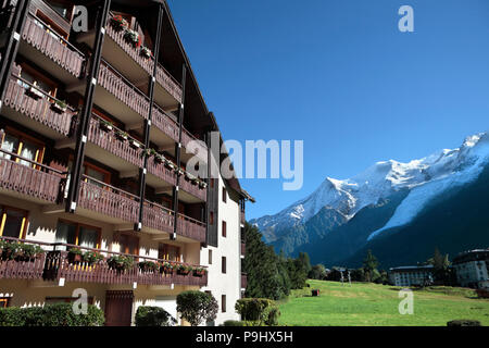 Traditional European alpine ski chalet hotel, view of the Alps in the distance.  Copy space in blue sky. Stock Photo