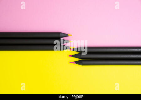The top views of black color pencils colored in shades of pink and yellow on colour paper background with copy space. Stock Photo