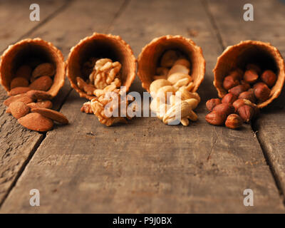 Ice cream cone with organic hazelnuts, cashews, almonds and walnuts on a rustic wooden table Stock Photo