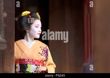 KYOTO, JAPAN - NOVEMBER 28, 2015: A woman in traditional Maiko dress looks out from a temple doorway. Stock Photo