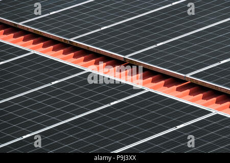 Sun reflection on a solar roof. black solar panel closeup on red roof Stock Photo