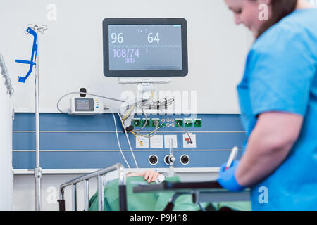 Nurse monitoring patient after operation in recovery room Stock Photo