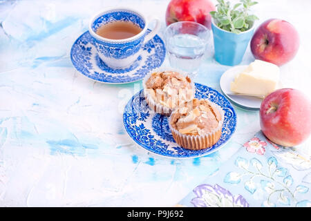 Homemade sweet muffins with almonds for breakfast. Tea and a glass of water in vintage blue dishes. Fruit and oil. Free space for text or a postcard Stock Photo