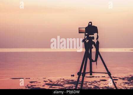 Dslr digital professional camera stand on tripod photographing sea, twilight sky and cloud landscape. nature background.image,picture on screen. dslr  Stock Photo