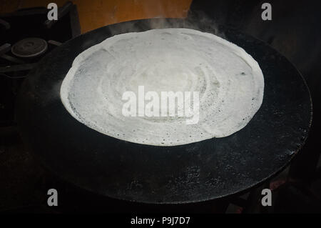 Stack of pancakes on a cast-iron frying pan. Top view. Flat lay. Dosa, or dosai. traditional Indian flatbread is fried on a large baking sheet Stock Photo