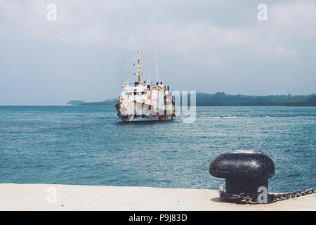 port of Genoa, old boat for water transport, abandoned, old and rusty, moored at the dock, in the background the sea of the gulf and small fishing boa Stock Photo