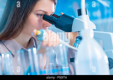 Young chemist in the laboratory. Scientist Using Microscope In Lab Stock Photo