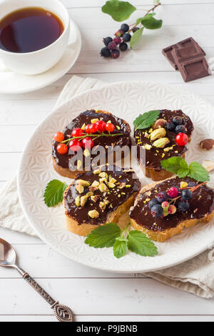 Sandwiches with chocolate paste, pistachio nuts and fresh berries on a plate Stock Photo