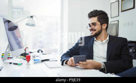 Businessman analyzing investment charts with calculator on office desk Stock Photo