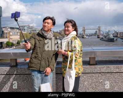 South Korean tourists taking a selfie in front of Tower Bridge on the river Thames, London, UK Stock Photo