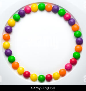 Circle of colored glazed candies on white background. candies melting in several rows, forming a rainbow Stock Photo
