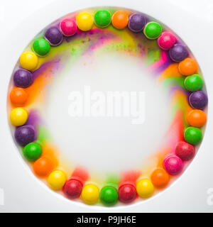 Circle of colored glazed candies on white background. candies melting in several rows, forming a rainbow Stock Photo