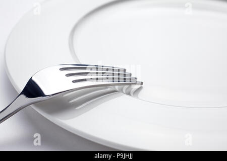 Fork on a empty plate, cutlery and copy space, on a white background Stock Photo