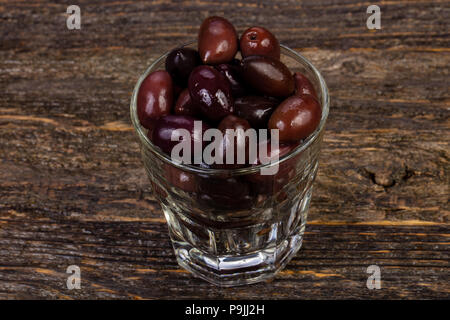 Black olives in the glass over wooden background Stock Photo