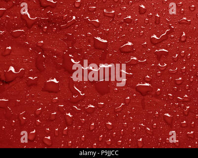 water drops on valiant poppy colored metallic surface Stock Photo