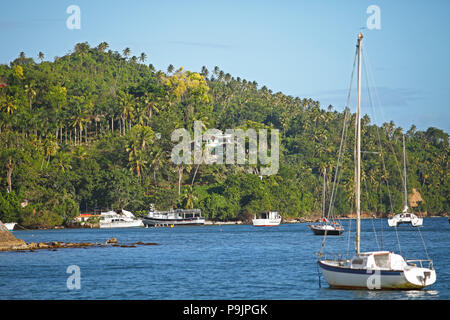 Boats bobbing in the bay of Samaná, behind the jungle of Santa Barbara de Samaná, Samaná province, Dominican Republic Stock Photo