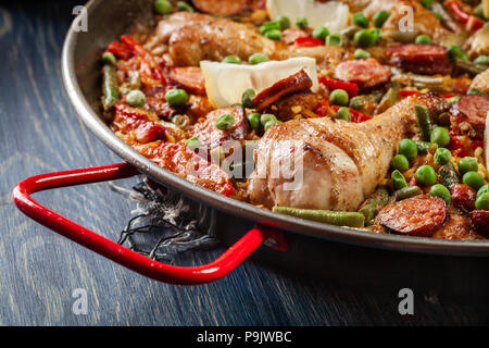 Traditional paella with chicken legs, sausage chorizo and vegetables served in paellera. Spanish cuisine Stock Photo
