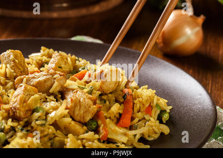 Fried rice nasi goreng with chicken and vegetables on a plate. Indonesian cuisine. Stock Photo