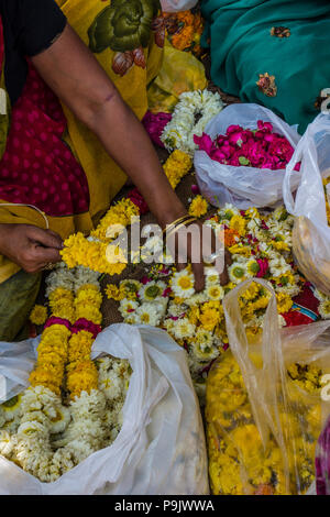 Indian woman making traditional flower garlands at a market stall in Old Delhi, Delhi, India
