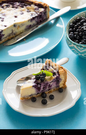 Tea time. Homemade blueberry cheesecake with ricotta cheese on blue paper background Stock Photo