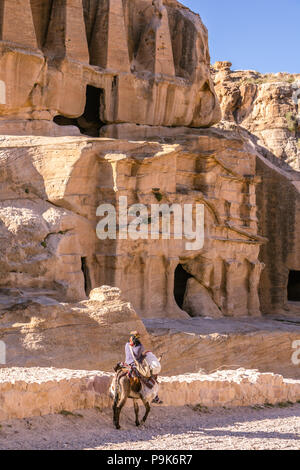 PETRA, JORDAN - APRIL 30, 2016: A bedouin young woman on a dunkey in the hidden city of Petra in Jordan. Stock Photo