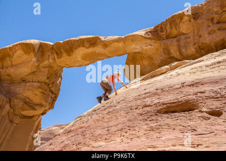 WADI RUM DESERT, JORDAN - APRIL 30, 2016: Woman climbing to the Burdah rock bridge in Wadi Rum desert - Valley of the Moon in Jordan. UNESCO World Her Stock Photo