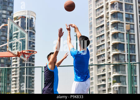 young asian adult players playing basketball on outdoor court. Stock Photo