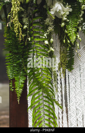 Wedding arch decoration with tropical flowers and plants, leaves of monstera and fern Stock Photo