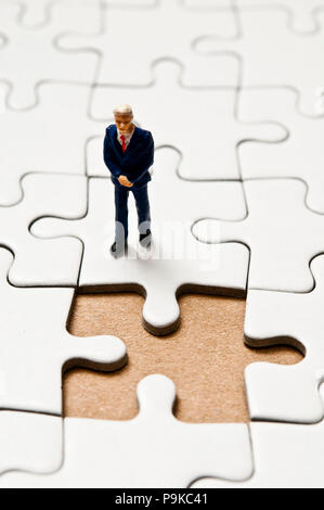 businessman miniature figurine standing on a jigsaw puzzle with a missing piece, business solutions concept Stock Photo