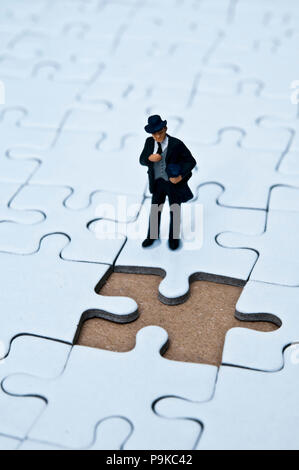 businessman miniature figurine standing on a jigsaw puzzle with a missing piece, business solutions concept Stock Photo