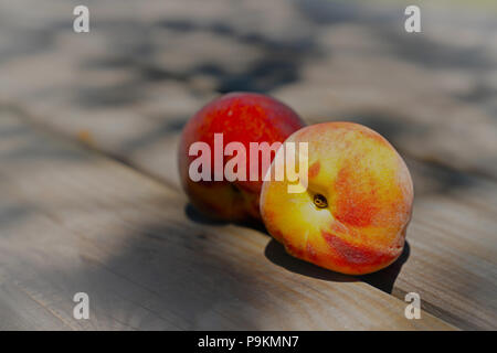 Two ripe peaches on wooden table Stock Photo
