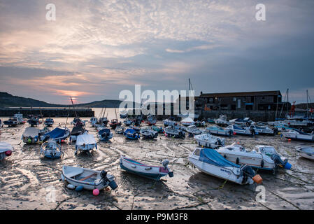 Lyme Regis, Dorset, UK. 19th July 2018. UK Weather:  Soft, muted sunrise colours in the morning sky are reflected at low tide at the historic Cobb Harbour in Lyme Regis. Credit: DWR/Alamy Live News Stock Photo