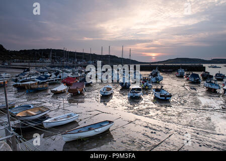 Lyme Regis, Dorset, UK. 19th July 2018. UK Weather:  Soft, muted sunrise colours in the morning sky are reflected at low tide at the historic Cobb Harbour in Lyme Regis. Credit: DWR/Alamy Live News Stock Photo