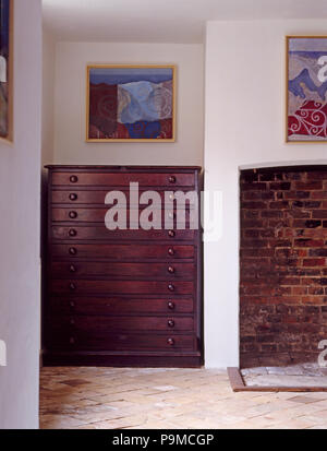 Picture above antique mahogany plans chest in country hall with old brick flooring Stock Photo