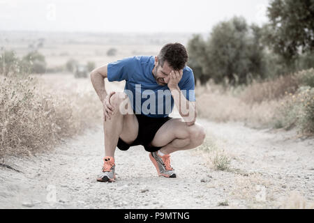 young sport man with strong athletic legs holding knee with his hands in pain after suffering muscle injury during a running workout training in aspha Stock Photo