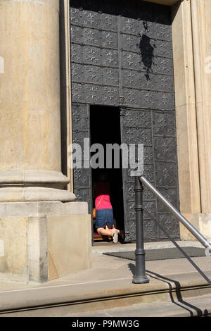 Woman kneeling down and praying in the doorway of a Catholic Church,Krakow,Poland. Stock Photo