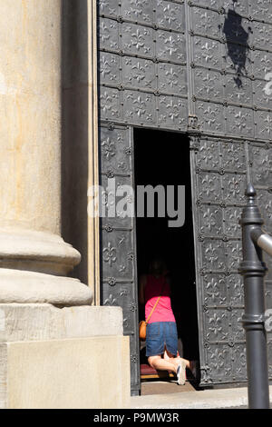 Woman kneeling down and praying in the doorway of a Catholic Church,Krakow,Poland. Stock Photo