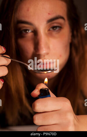 a young drug-addict woman lheated spoon with lighter Stock Photo